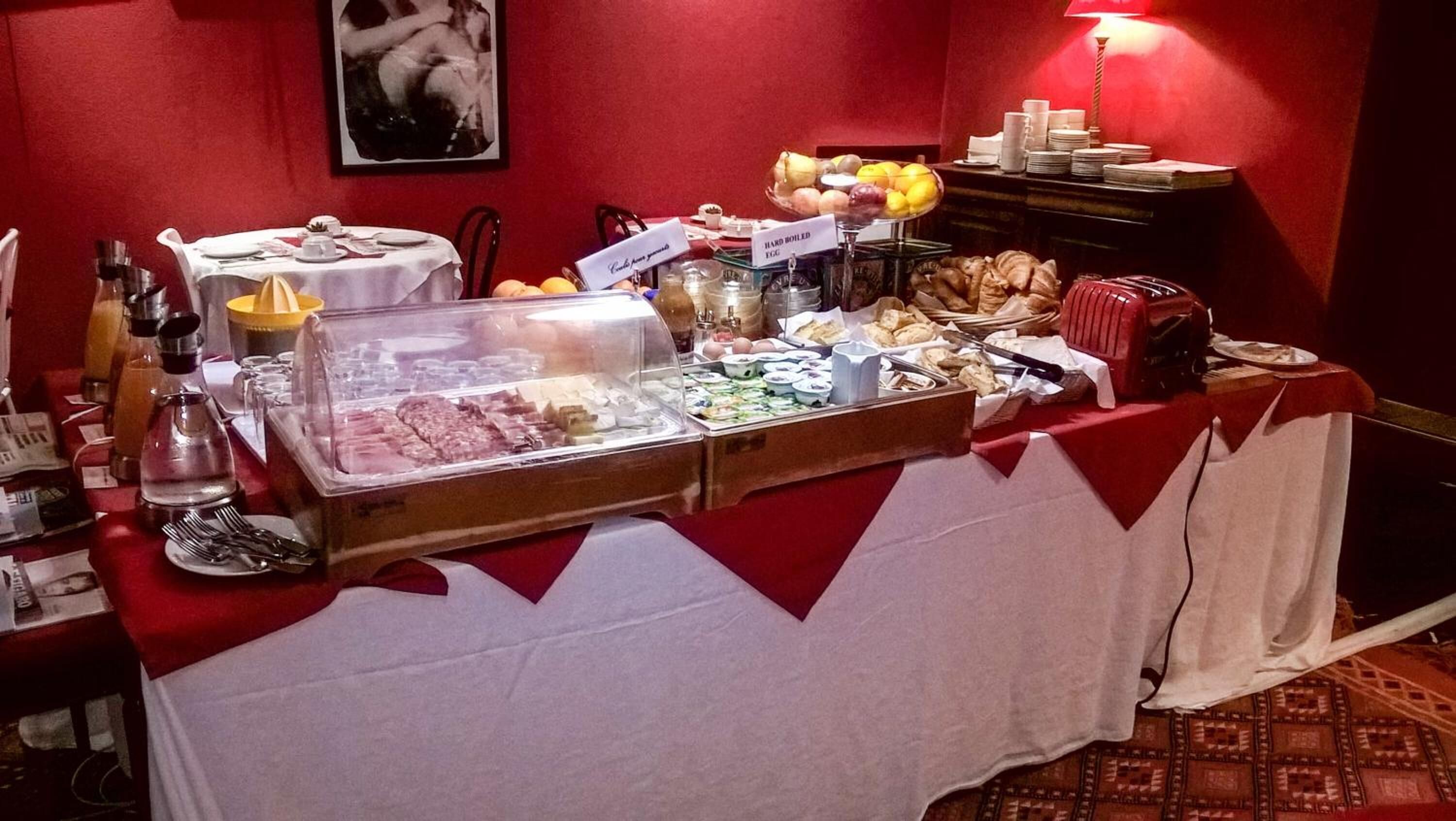 A buffet setup with various food items and beverages, including hard-boiled eggs, fruits, and pastries.
