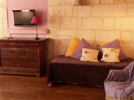 Un dormitorio con una cama, un aparador, un televisor y una lámpara.