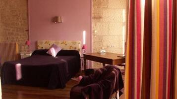 A bedroom with two beds, a wooden ceiling, a stone wall, and a small table.