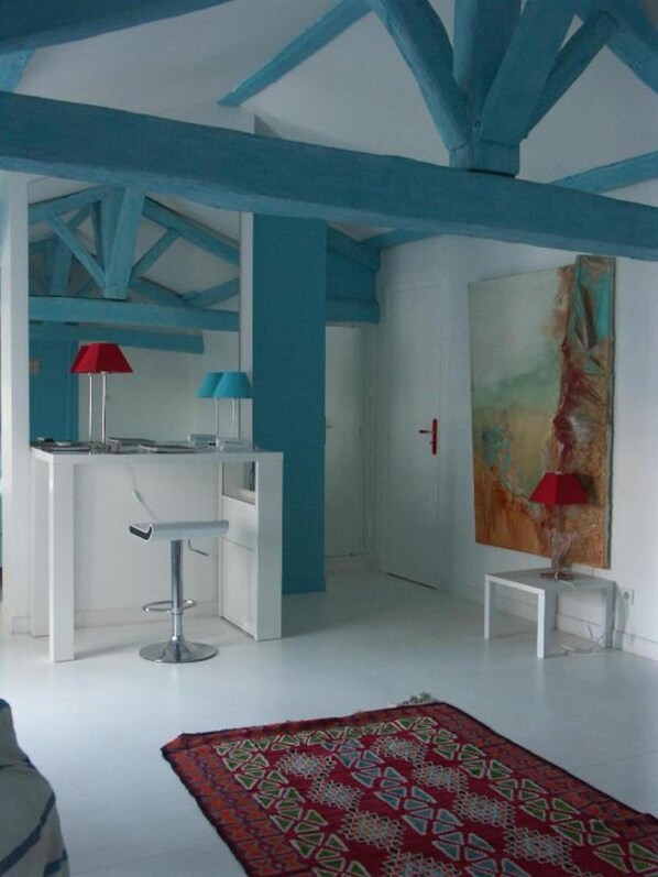 A modern room with a white desk, two chairs, a red lamp, and a large abstract painting on the wall. - Hôtel du Palais (Angouleme)