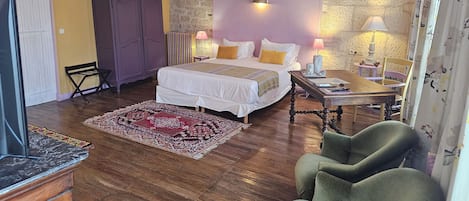 A bedroom with a bed, bedside lamps, a wooden table, a chair, and a patterned rug.