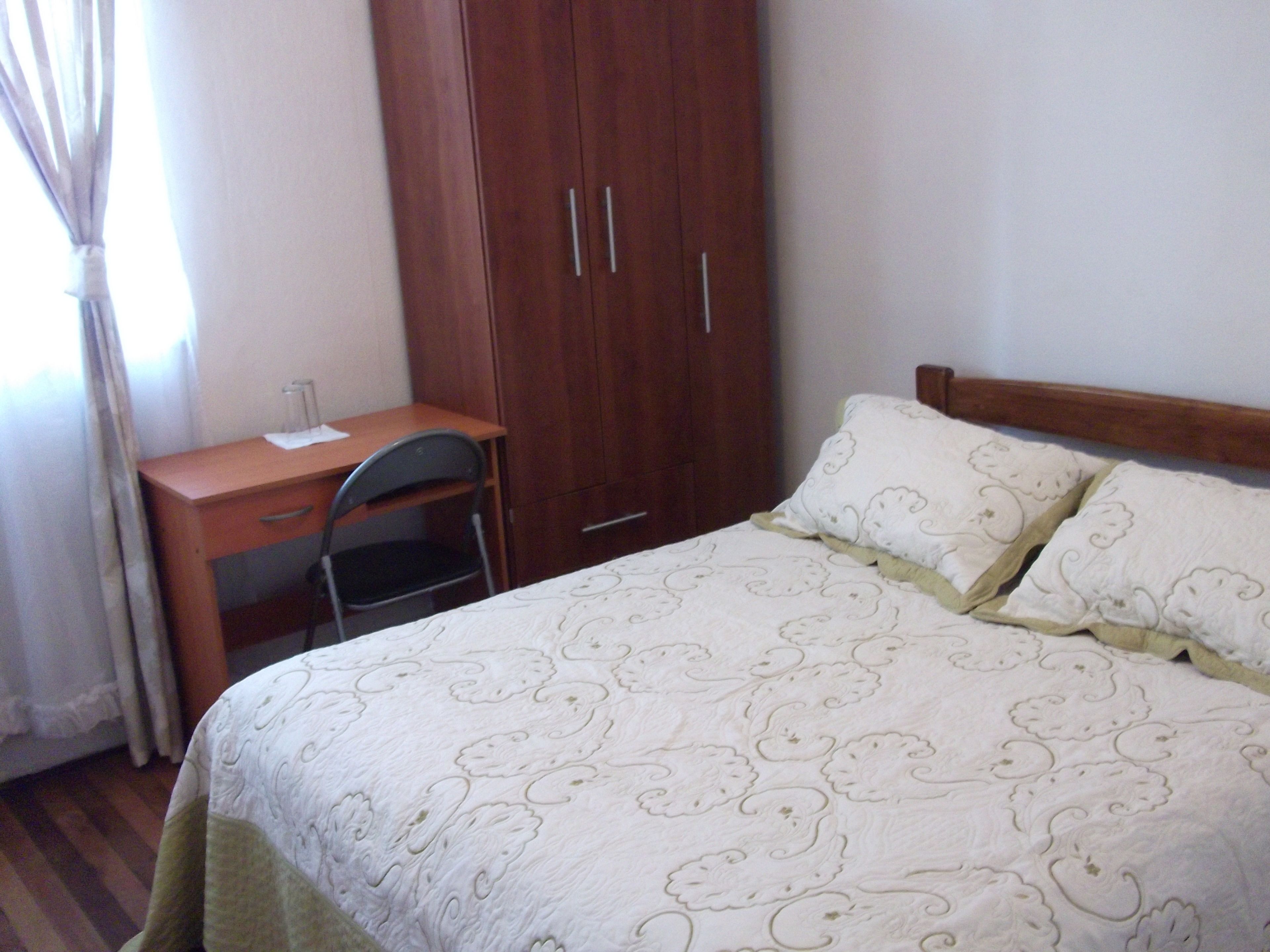 Un dormitorio con cama, escritorio y armario.