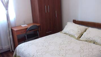 Un dormitorio con cama, escritorio y armario.