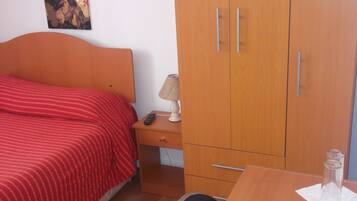 Une chambre à coucher comprenant un lit, une table de chevet, une lampe, une armoire et un bureau avec une chaise.