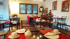 Un comedor con mesas dispuestas para el desayuno, con una variedad de frutas y bebidas.