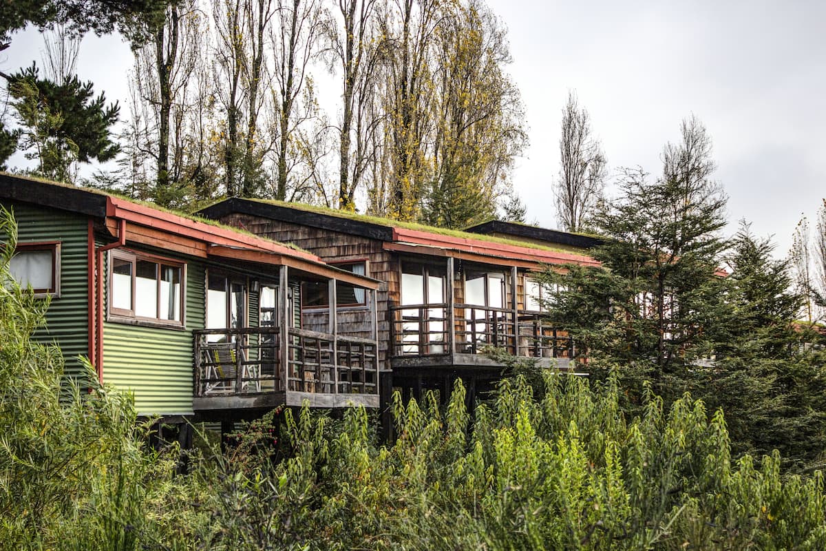 A row of cabins with wooden balconies, surrounded by dense vegetation and tall trees.