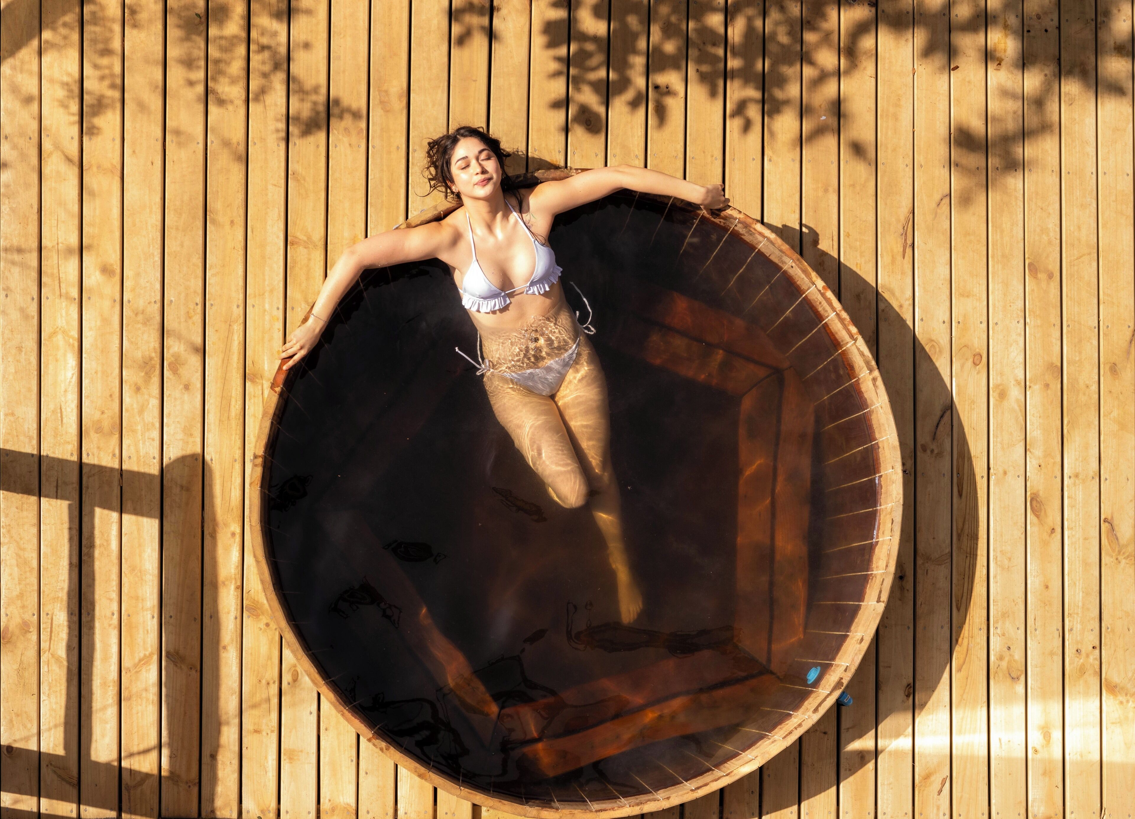 A person lying inside a wooden barrel-shaped structure.