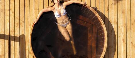 A person lying inside a wooden barrel-shaped structure.