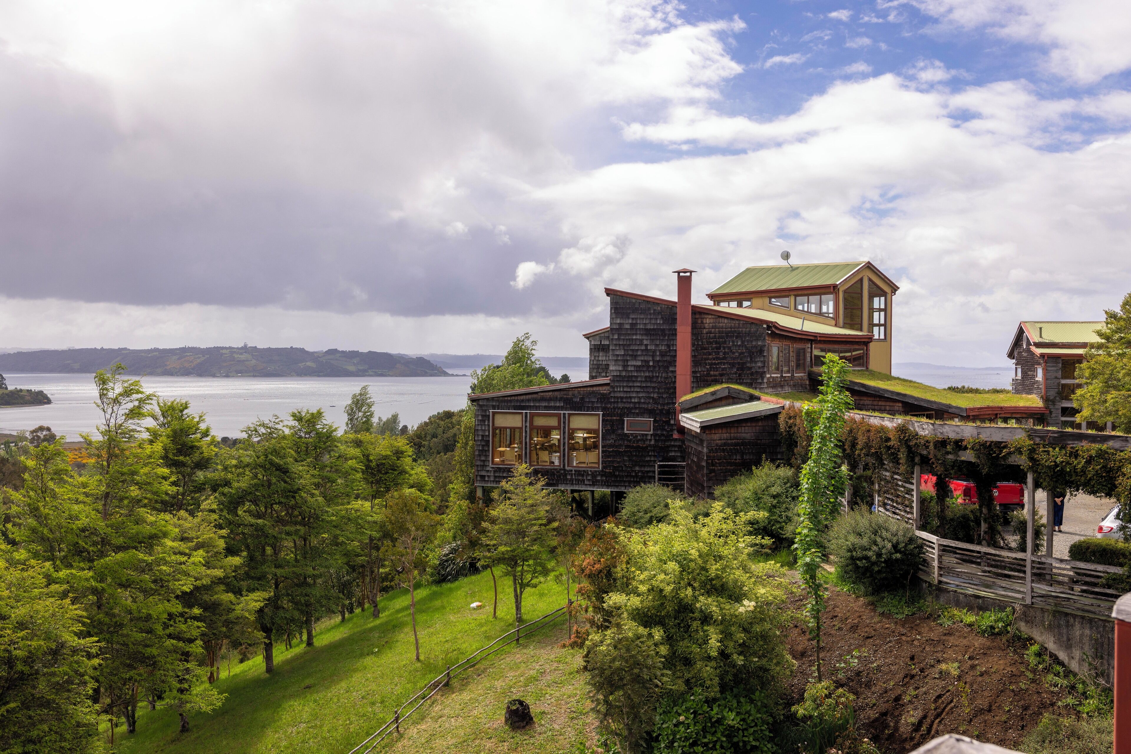 A modern house with a stone facade, large windows, and a view of the water.