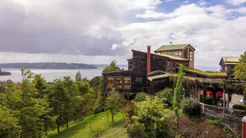 A modern house with a stone facade, large windows, and a view of the water.