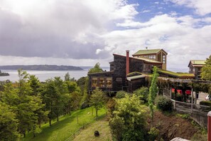 A modern house with a stone facade, large windows, and a view of the water.