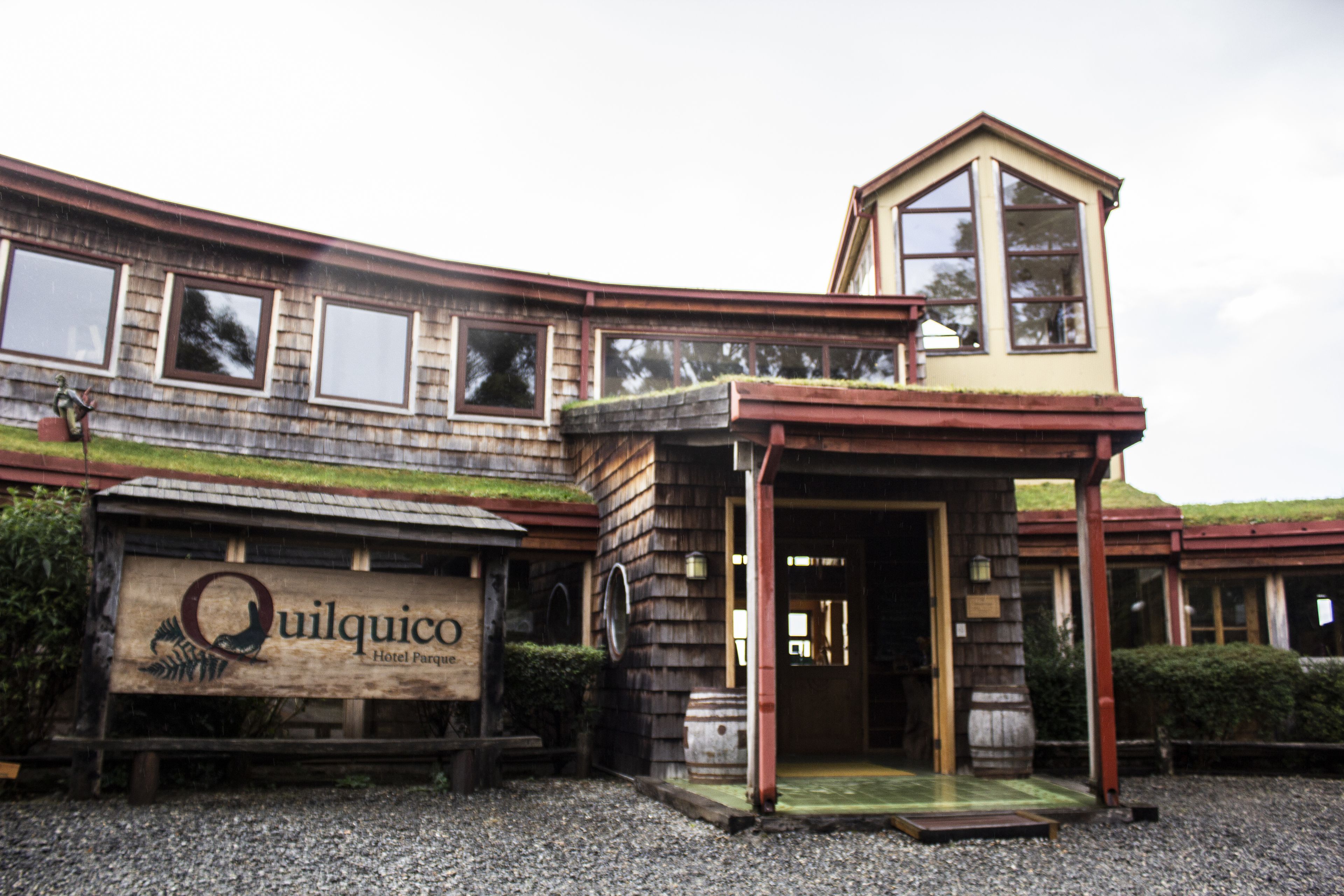 Un hotel con facciata in legno, un ingresso evidente e un cartello che riporta la scritta "Quilquico Hotel Parco".
