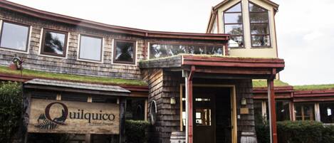 Un hotel con fachada de madera, una entrada destacada y un letrero que dice 'Quilquico Hotel Parco'.