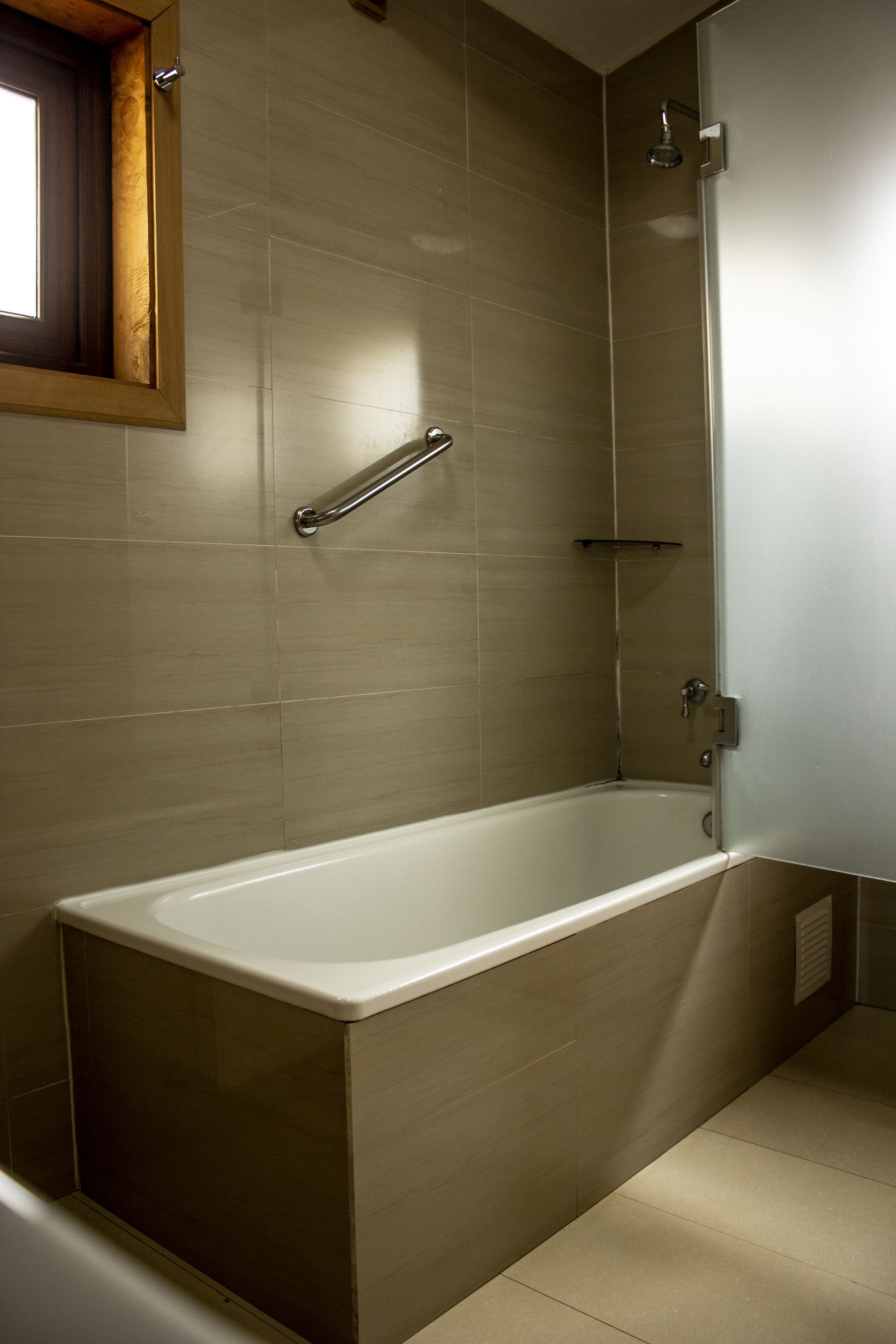 A modern bathroom with a bathtub, a shower, and a window.