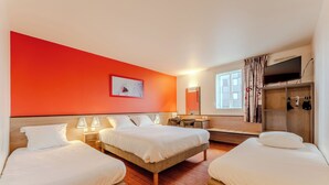 Habitación de hotel con dos camas, un escritorio, un espejo, un televisor y un armario.