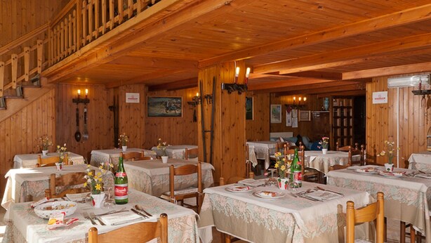 A wooden interior with multiple dining tables set for meals, wooden chairs, and a staircase leading to an upper level. - Hotel Del Postiglione (Ischia)