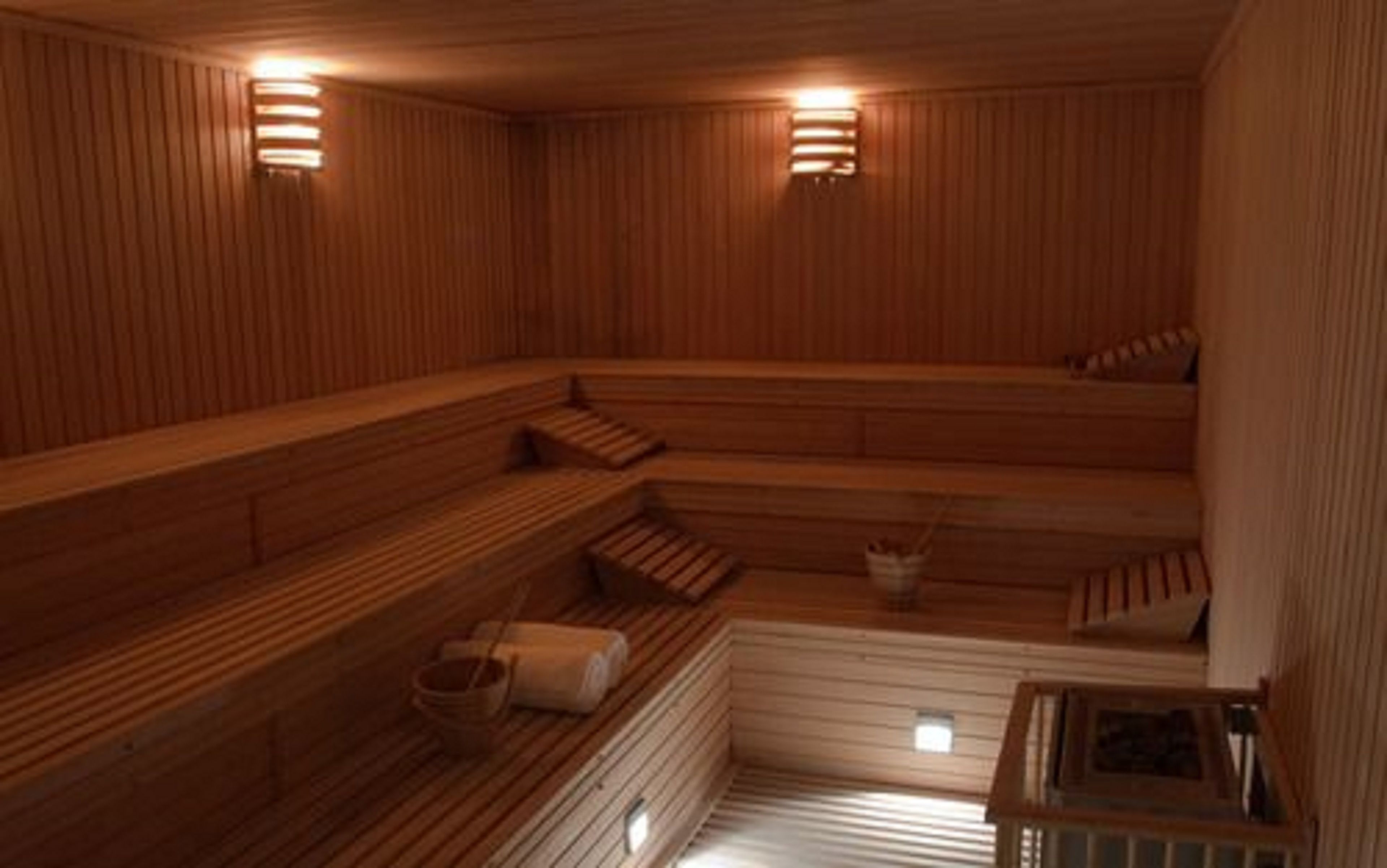 A sauna with wooden benches and two wall-mounted lights.