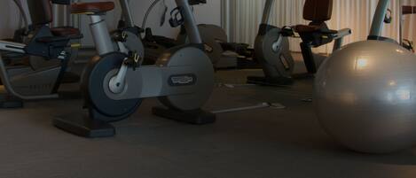 A gym with stationary bikes and an exercise ball.