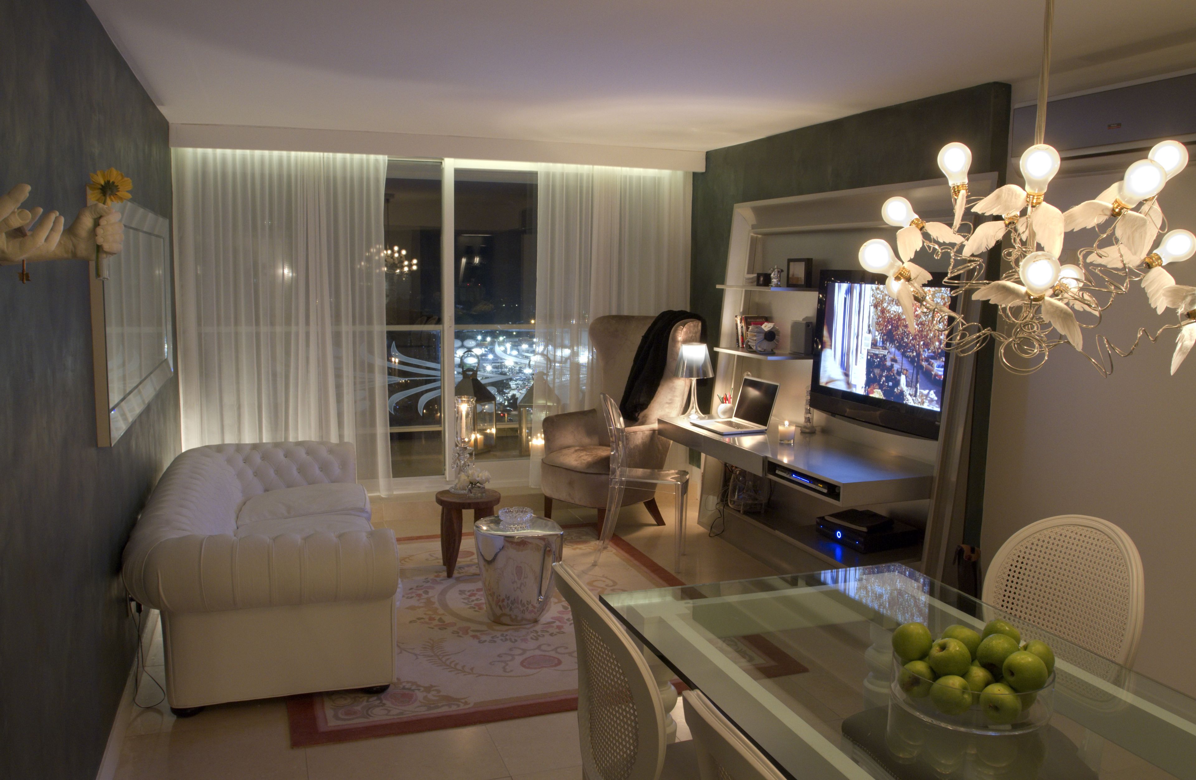 Una sala de estar moderna con un sofá, una mesa de centro de vidrio, un televisor y una lámpara decorativa.