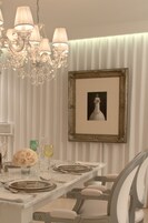 Un comedor con candelabro, obras de arte enmarcadas y una mesa preparada para cuatro.