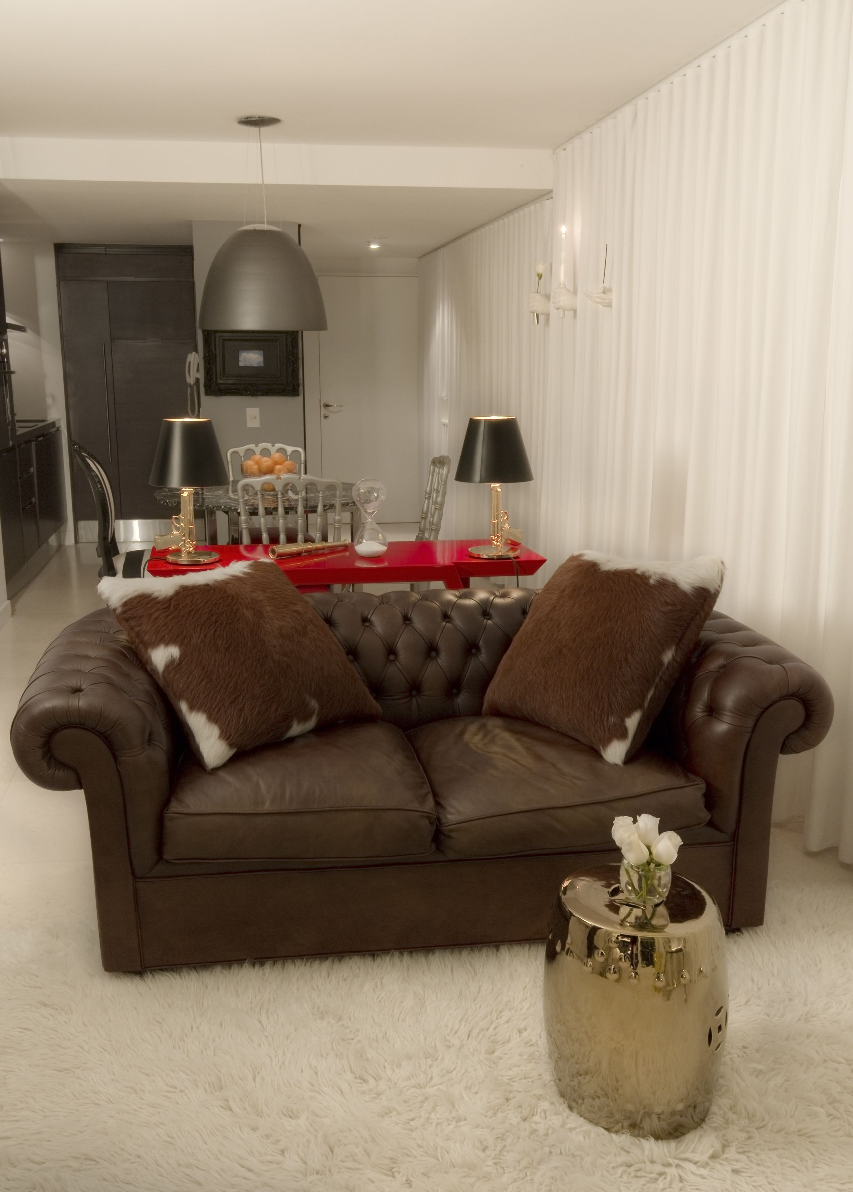 A modern living room with a brown leather sofa, two black lamps, a glass coffee table, and a white furry rug.