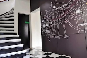 Escada que leva a um quarto com piso quadriculado em preto e branco e um mapa na parede.
