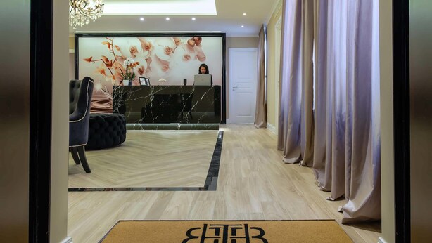 Una zona de recepción con mostrador de mármol, un sillón cómodo y un mural floral.