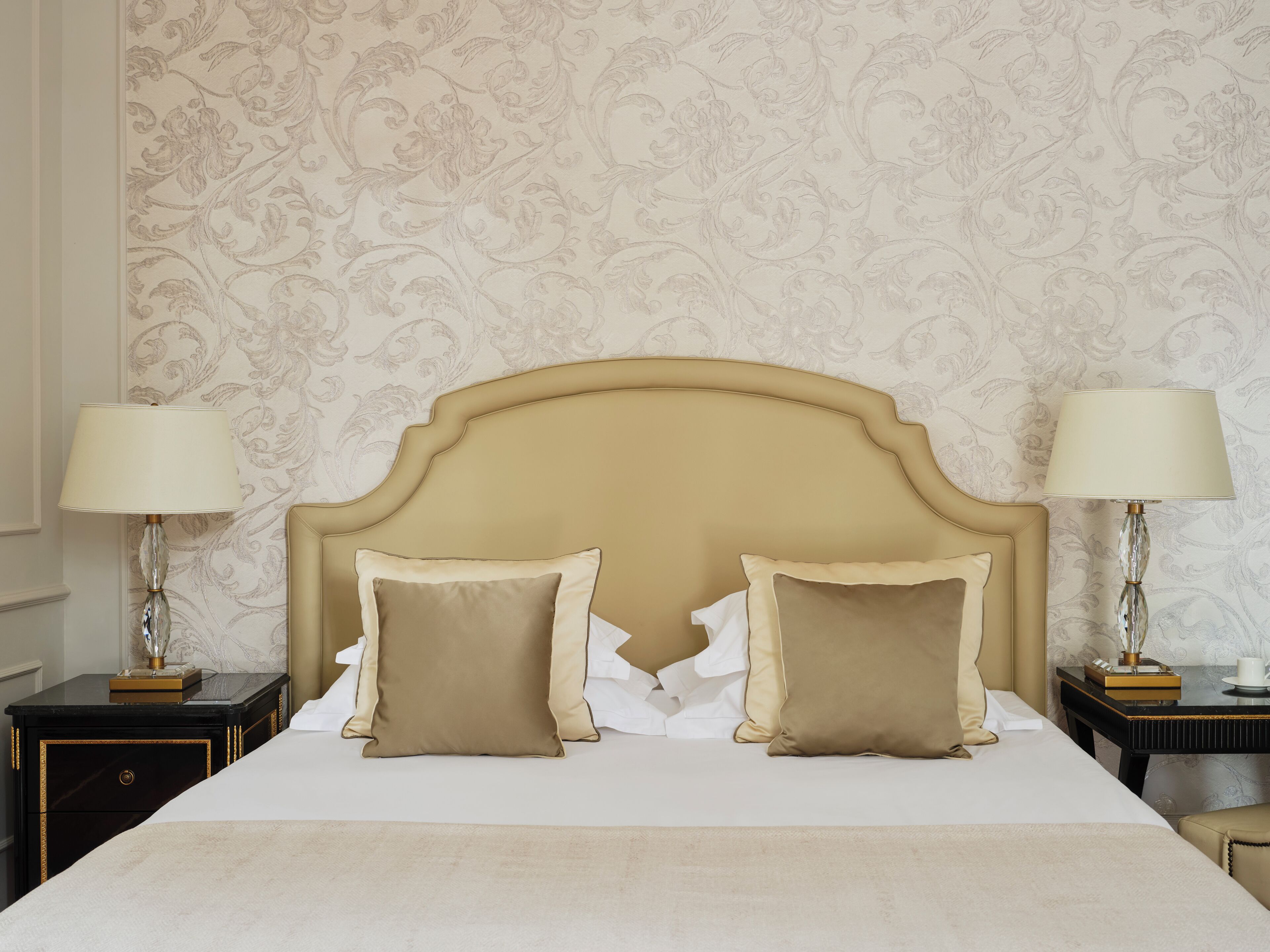 A bed with a headboard, two bedside tables, and lamps.