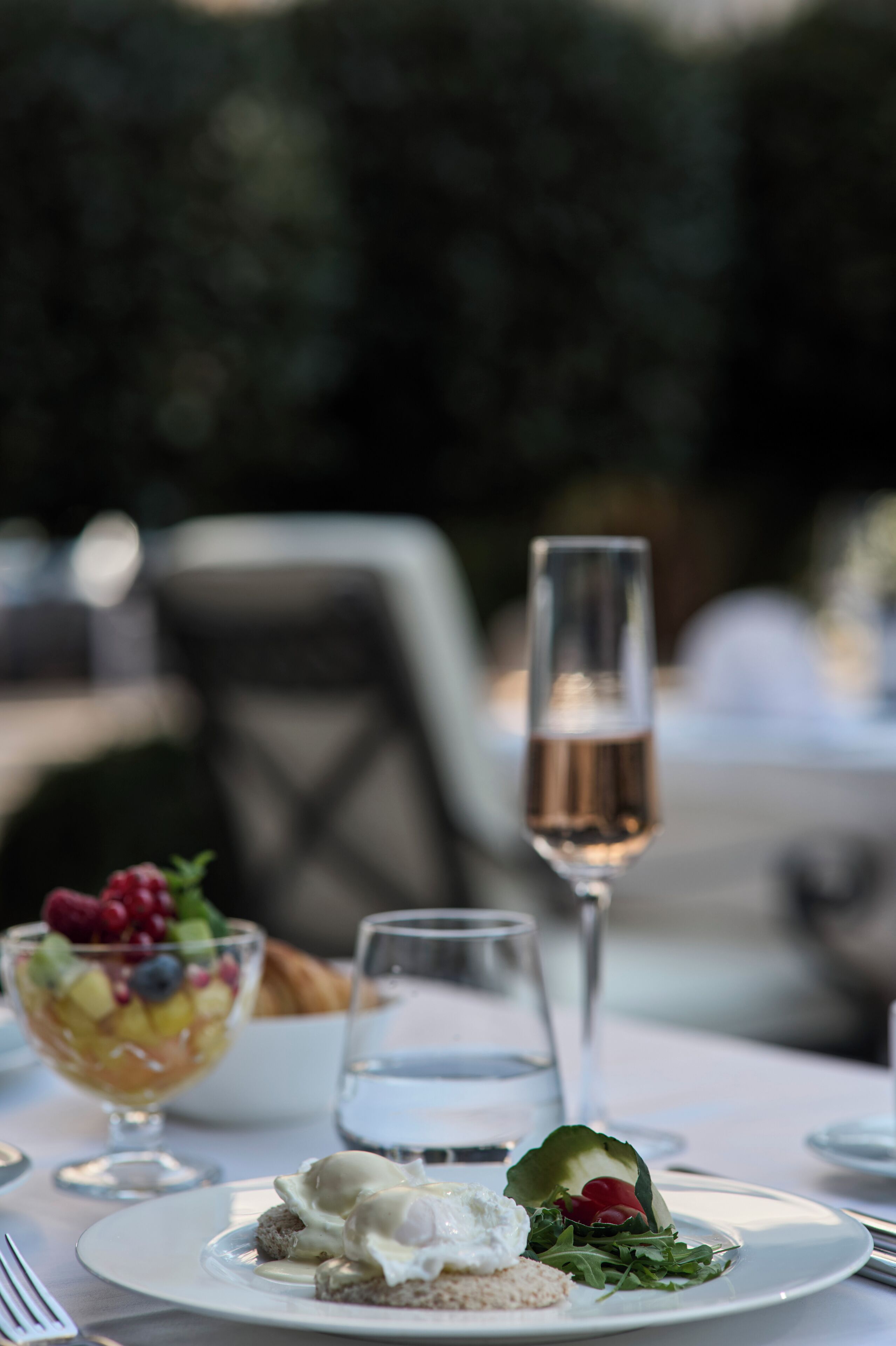 A dining table with a dessert bowl, a glass of water, and a glass of champagne.