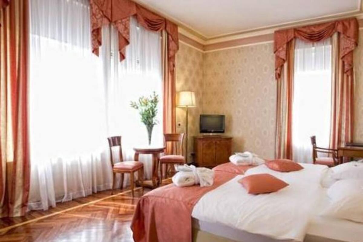 Una habitación de hotel con una cama, televisión, escritorio y silla.