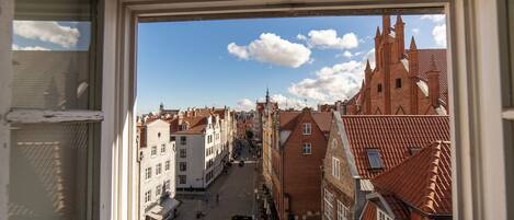 A view through a window of a street with traditional buildings, a clear sky, and a few pedestrians.