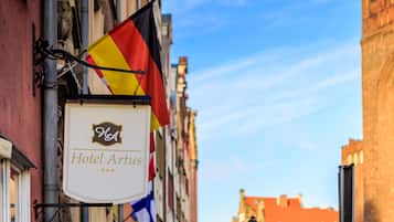 A hotel sign with the name "Hotel Artus" and multiple flags.