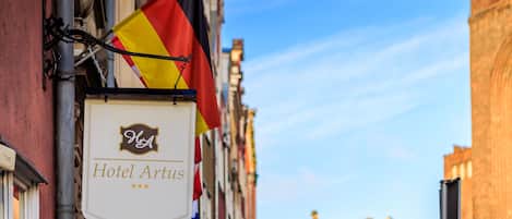 A hotel sign with the name "Hotel Artus" and multiple flags.