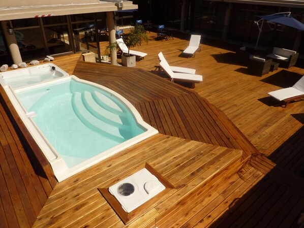 Una piscina al aire libre, sombrillas, sillones reclinables de piscina