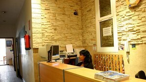 Una mesa de recepción con una computadora, un extintor y una ventana con un cartel.
