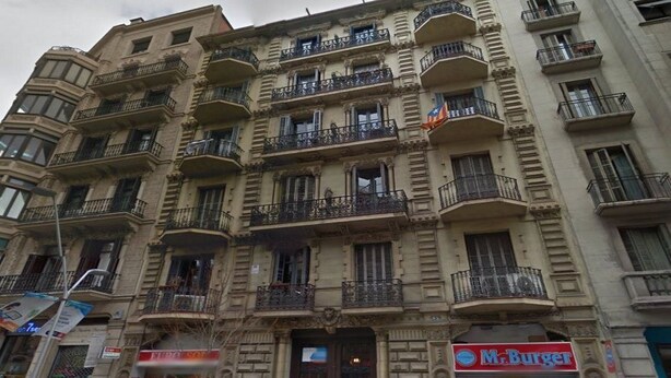 Un edificio de varios pisos con balcones, un letrero de restaurante a la vista y una tienda.