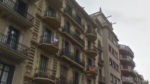 Un edificio de varios pisos con balcones, una señal de calle y un paso de peatones.