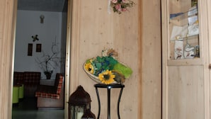 A wooden interior with a chandelier, a floral arrangement, and a cabinet with glass doors. - Bellavista (Comelico Superiore)