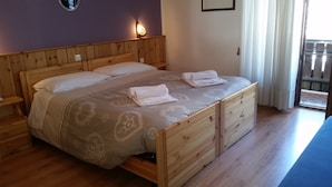 A double bed with a wooden frame, a beige patterned bedspread, and two folded towels. - Bellavista (Comelico Superiore)