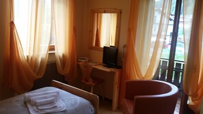 A bedroom with a bed, a desk, a chair, and a window with curtains. - Bellavista (Comelico Superiore)
