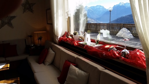 A cozy room with a sofa, a table with candles, and a view of a snowy landscape through a window. - Bellavista (Comelico Superiore)
