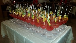A table with multiple glasses of red drinks, each garnished with fruit slices and skewers. - Bellavista (Comelico Superiore)
