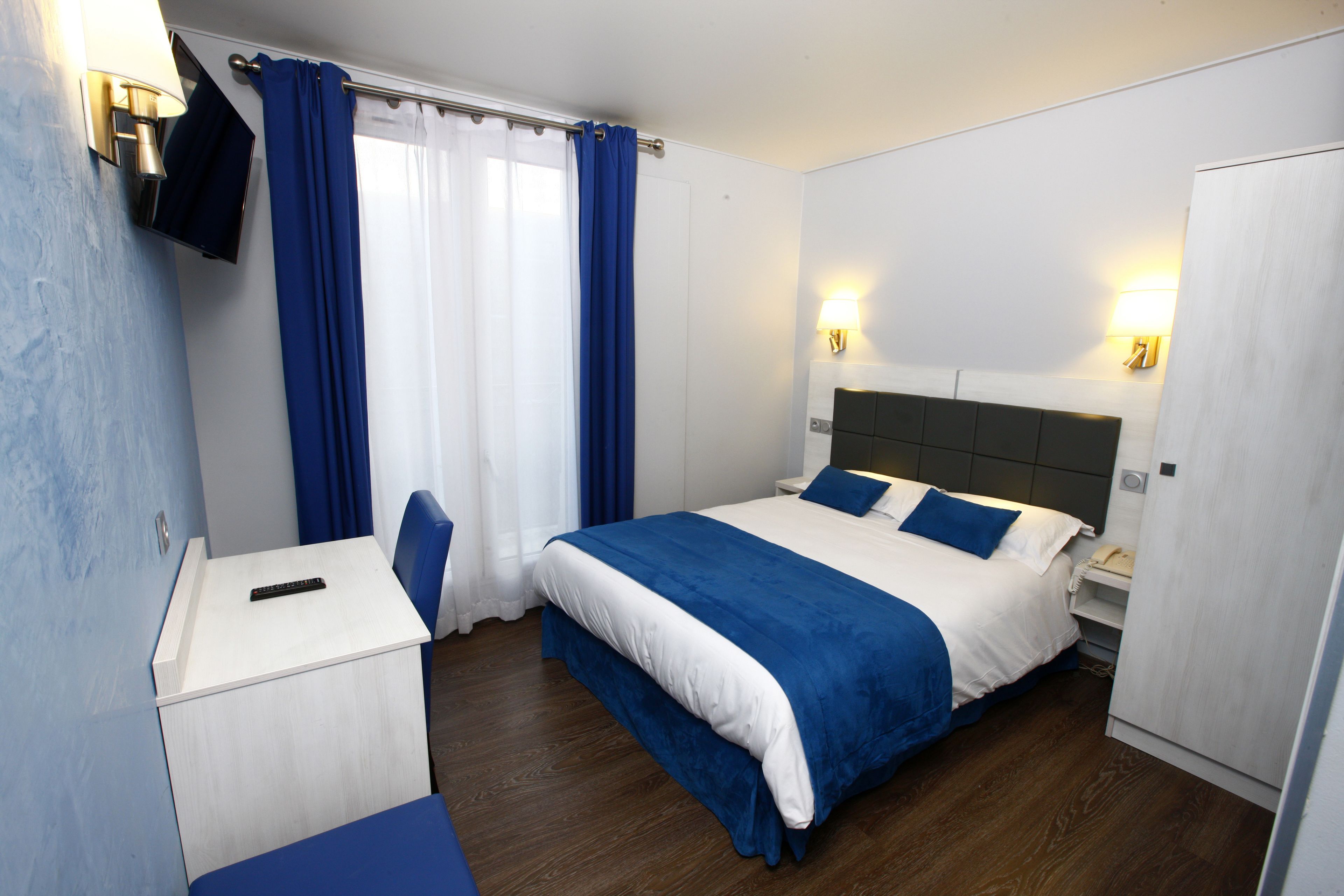 Une chambre d’hôtel comprenant un lit, des tables de chevet, un bureau et une armoire.