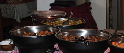 A buffet table with various dishes in black serving containers, a checkered tablecloth, and a sign in the background.