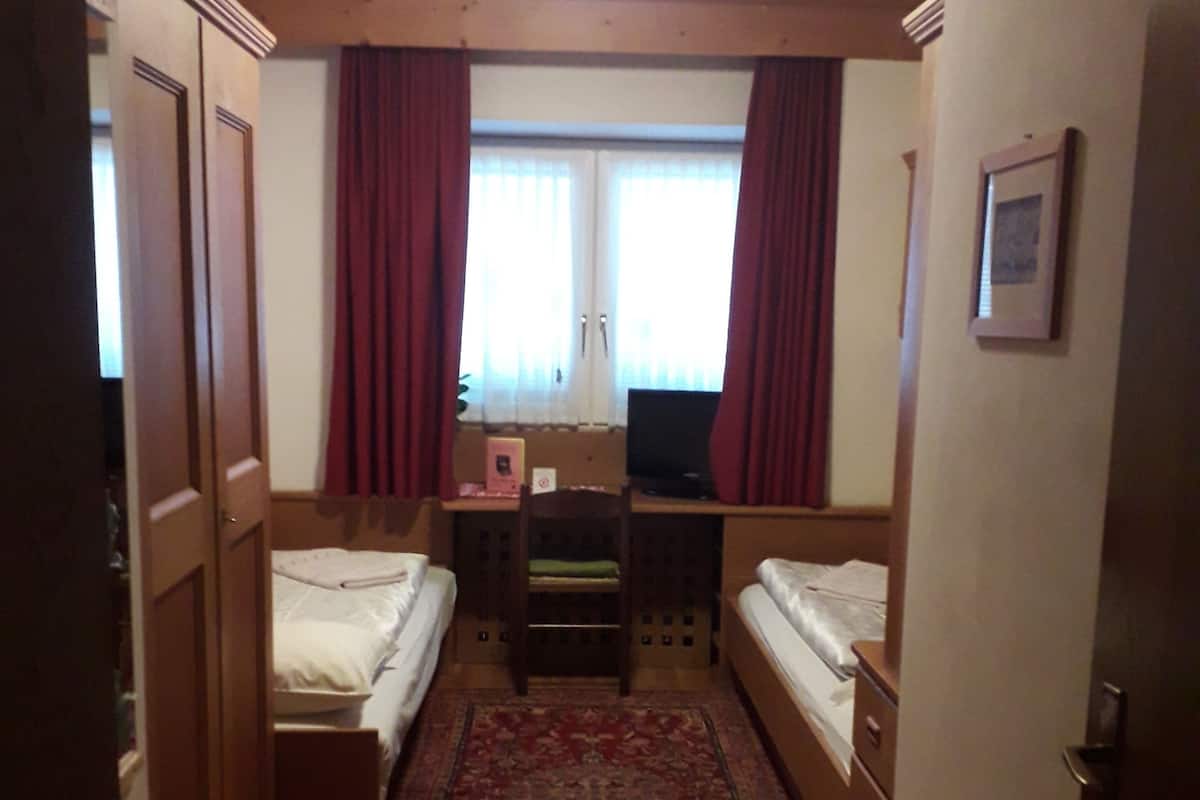 A compact room with two single beds, a desk, and a television.