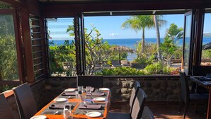 A dining area with a table set for four, overlooking a beach with palm trees and the ocean. - Volivoli Beach (Rakiraki)