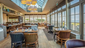 Un restaurante espacioso con techos altos, ventanas amplias y diversas opciones de asientos.