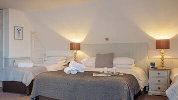 A hotel room with two beds, a nightstand with a lamp, and a small table with a tray.