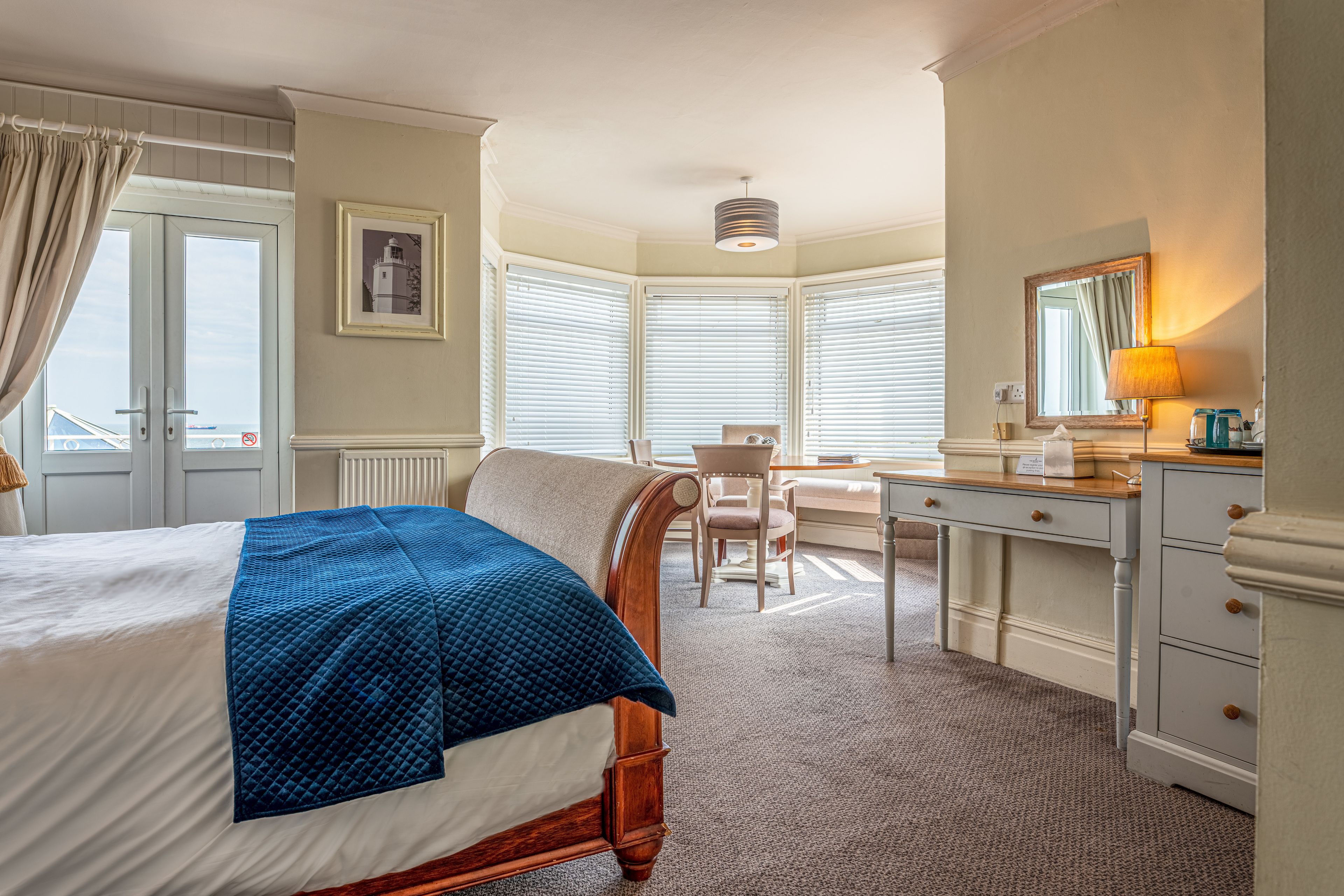 A hotel room with a bed, a desk, a chair, and a window with blinds.