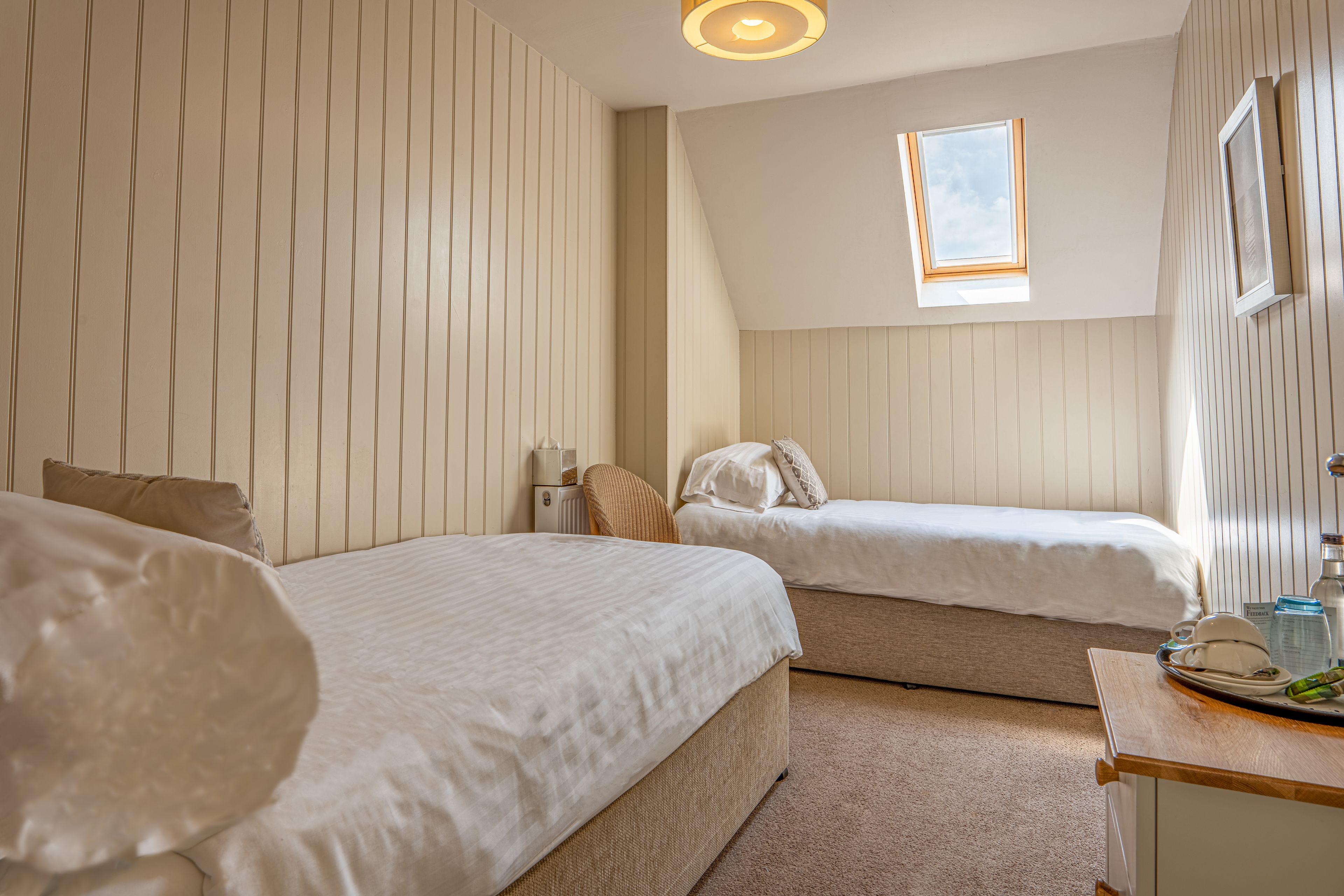 Een slaapkamer met twee bedden, een tafeltje, een radiator en een raam.